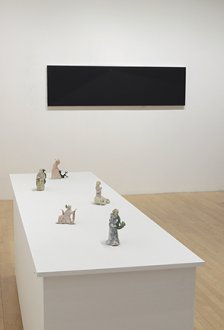 5 sculptures on pedestal and dark painting on wall